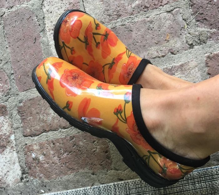 Bright yellow clogs adorned with vibrant orange flowers, perfect for a bold fashion statement.