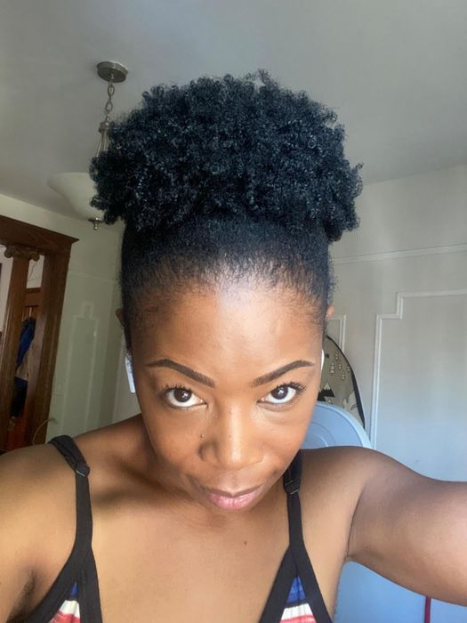 A reviewer with tightly curled hair styled in a puff