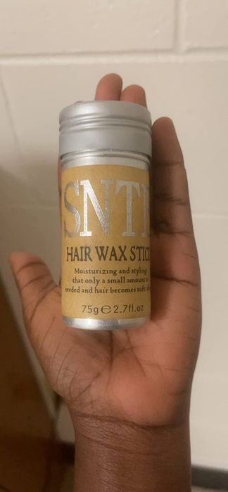 A reviewer holds the hair wax stick in their hand.
