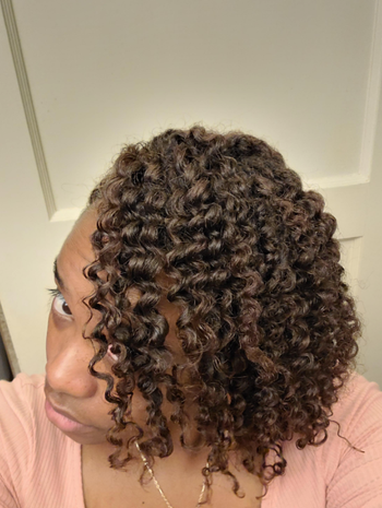 A reviewer showcasing their well-hydrated and well-defined curls up close.