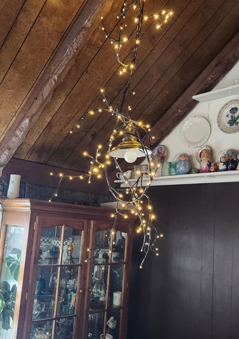 A string of lights wrapped around a wooden beam in a cozy room, complementing a display cabinet.