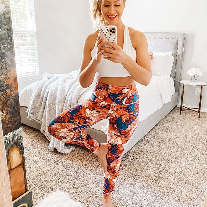 a reviewer sporting floral leggings while holding a yoga pose
