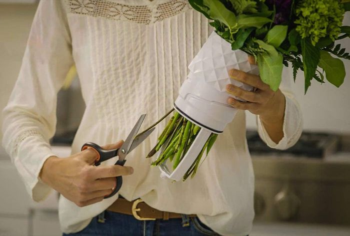 A model trimming flower stems and draining water from the vase with ease