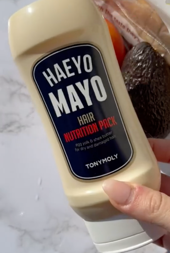 A model holding a bottle that resembles a tube of mayonnaise