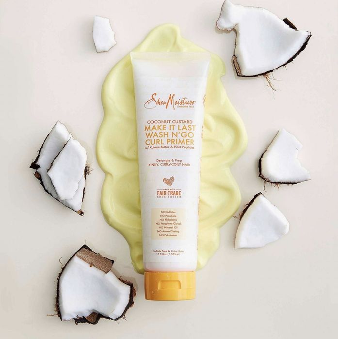 A tube of creamy, gel-based curl primer adorned with cut coconuts