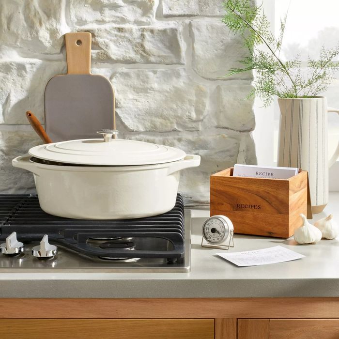 The cream-colored Dutch oven resting on a stove.