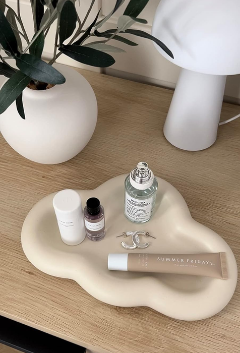 A cloud tray featured by a reviewer, adorned with jewelry, lip gloss, and perfumes.