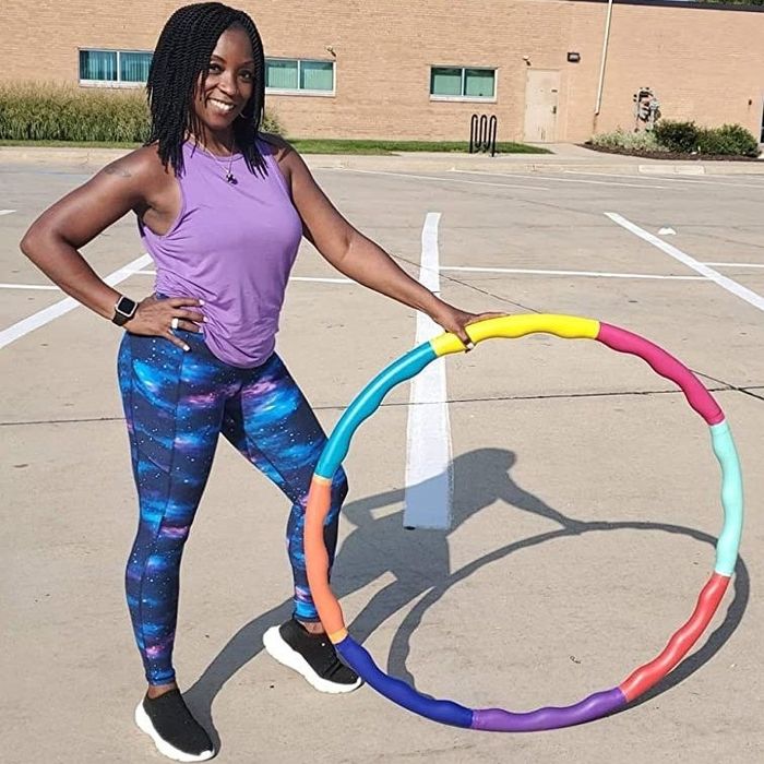 A reviewer models galaxy print leggings while holding an exercise hoop, combining style with a fun workout accessory.