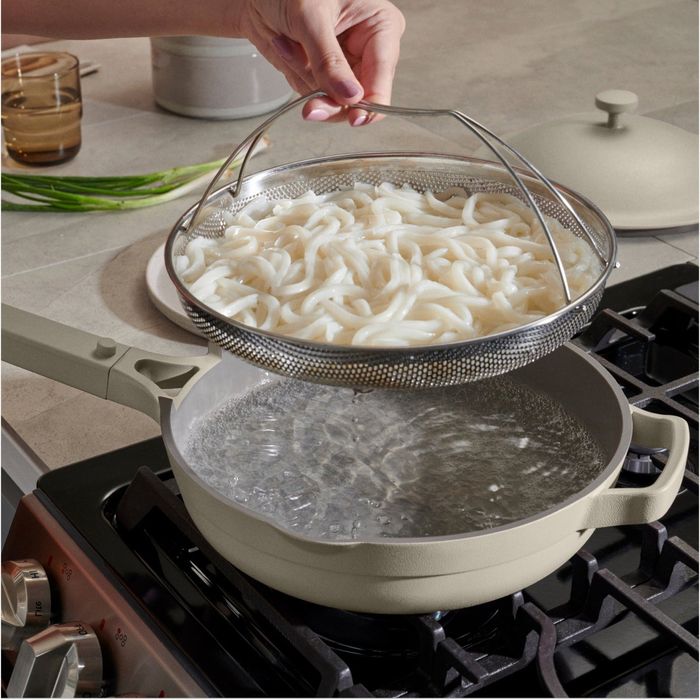 A model is shown draining noodles using the included colander