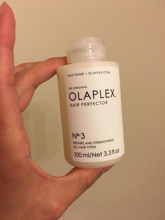 A reviewer holds the product bottle in their hand, showcasing its design.
