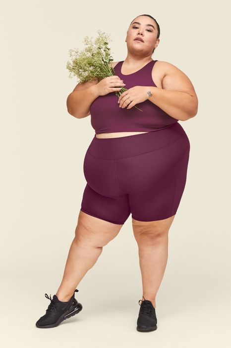 a model wearing purple bike shorts while holding a bouquet of flowers