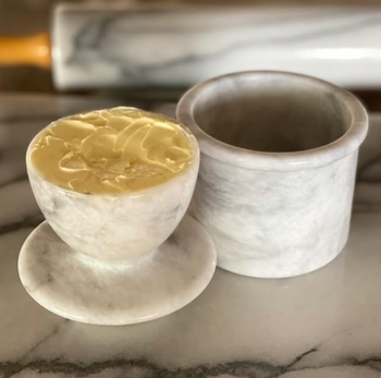 Two marble containers placed on a countertop, one filled with butter and the other with water, offering an elegant touch to the space.