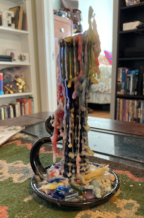 A beautifully crafted multi-layered candle with wax drips resting on an elegant holder.