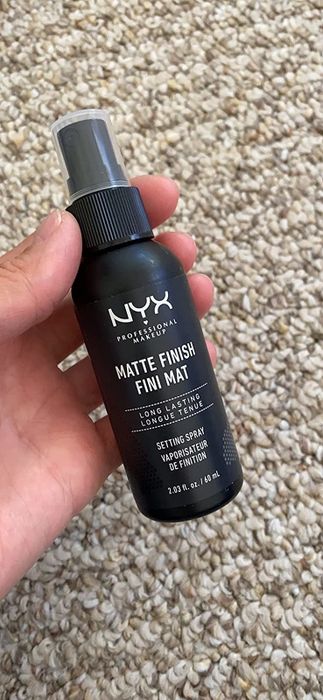 A reviewer holding the setting spray bottle