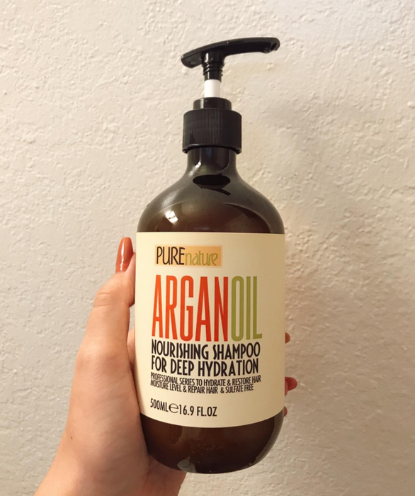 A reviewer holding the bottle of shampoo, demonstrating the product.