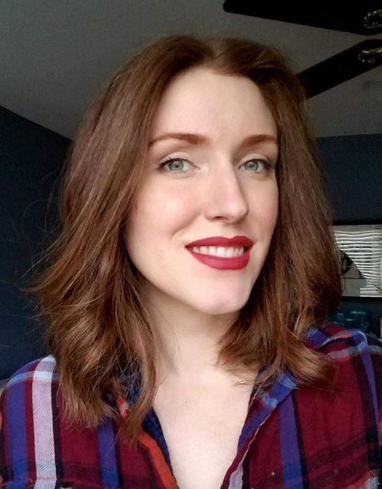 A reviewer wearing red matte lipstick on their lips