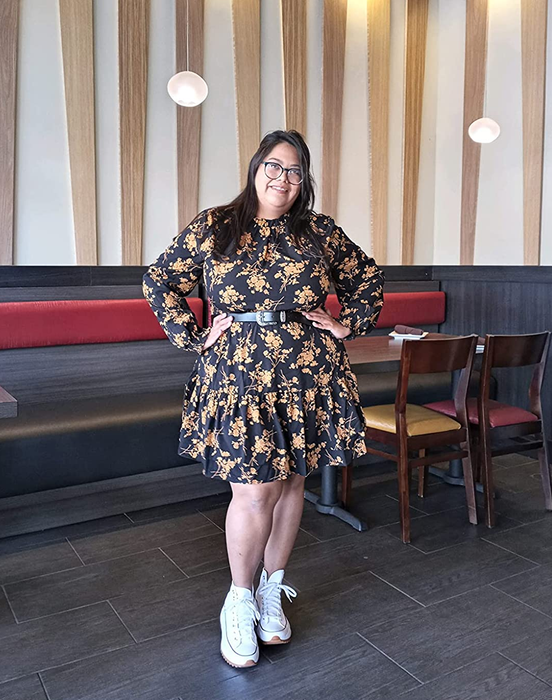 A reviewer’s photo of them posing in a black and yellow floral dress