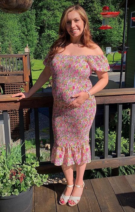 A reviewer wearing the dress adorned with a floral pattern.