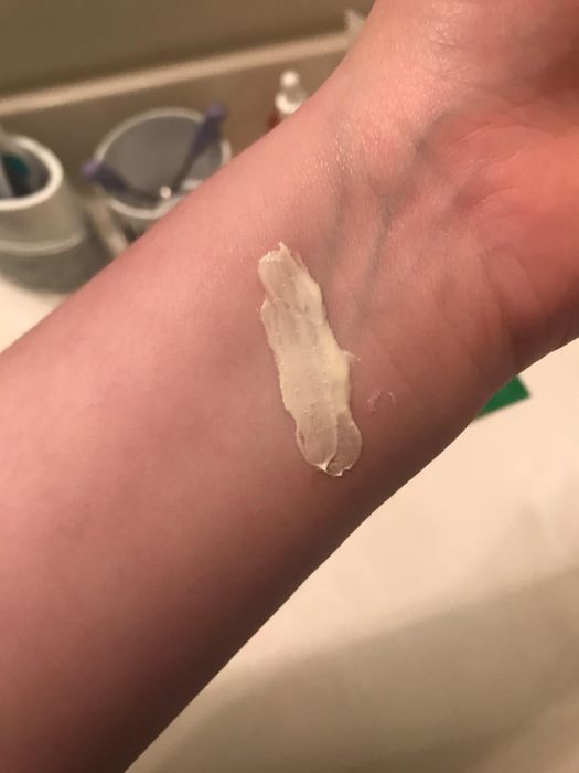 A reviewer demonstrating the thick consistency of the cream on their inner arm
