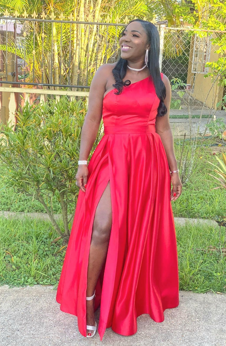 Reviewer in a stunning red gown with a high slit, smiling in an outdoor environment. Not a recognized public figure