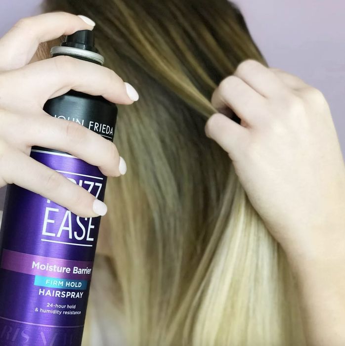 A person is spraying hairspray onto their hair.