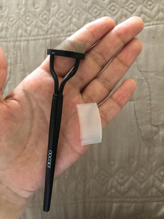 A reviewer holding their eyelash comb separator along with the comb's protective cover