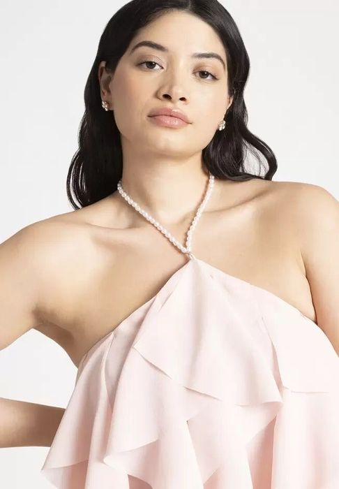 A model dressed in an elegant outfit featuring a pearl neckline and intricate ruffled details