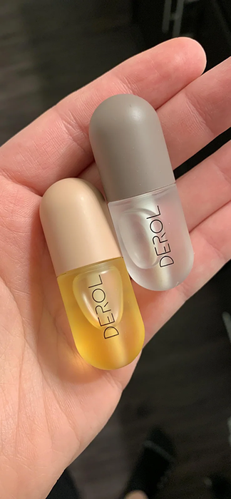 The reviewer can be seen holding a pair of lip plumping products.