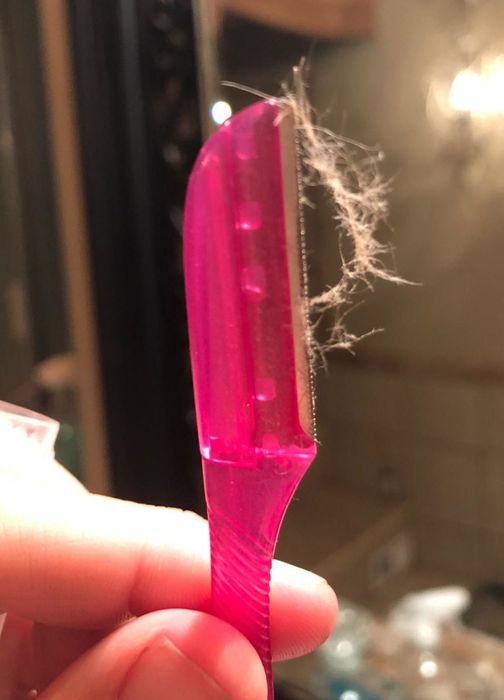 A reviewer showcasing the razor after using it to remove facial hair