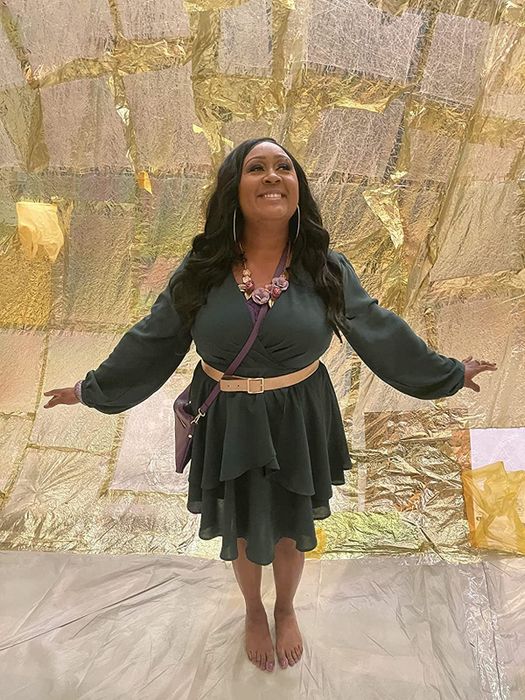 A reviewer is pictured wearing the dark green long-sleeved wrap dress.