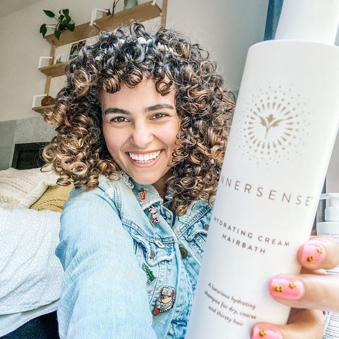 A person showcasing the Hydrating Cream Hairbath bottle