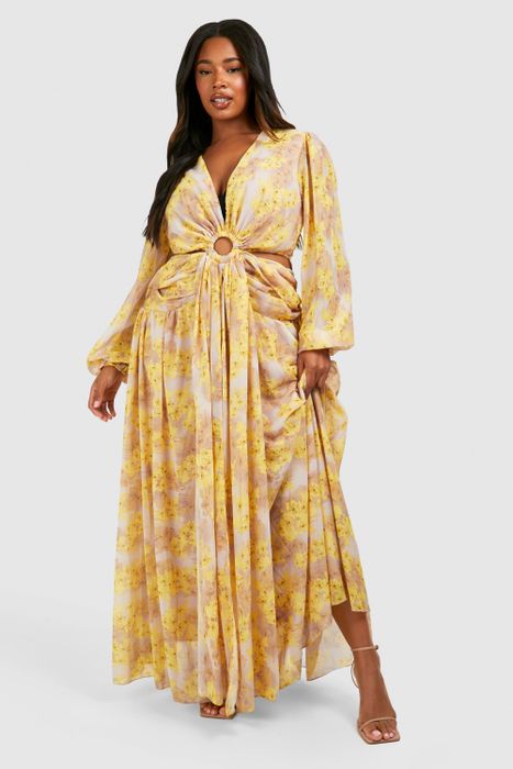 A person wearing a floral dress with a fitted waist, posing confidently for the camera.
