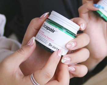 The model is holding a twist-open jar of the product.