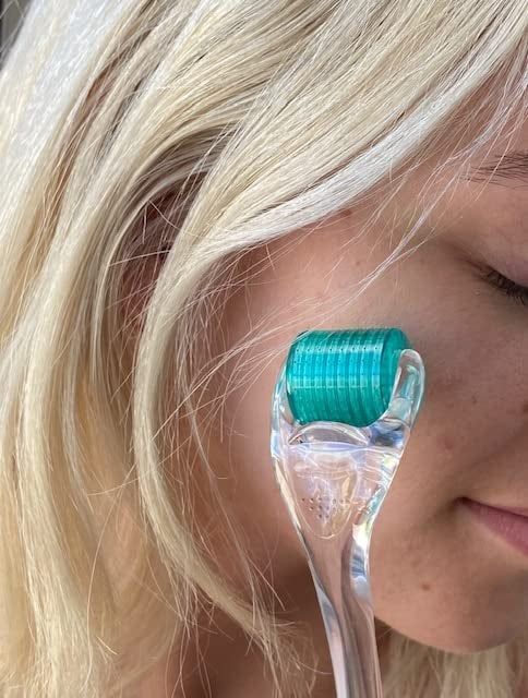 An individual applying a microneedling tool to their cheek, showcasing an effective skincare regimen