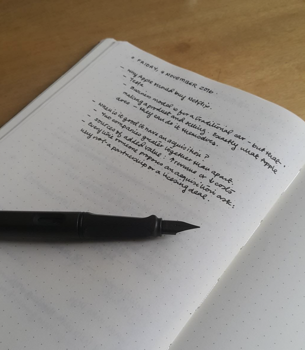 A fountain pen resting on top of a journal filled with notes.