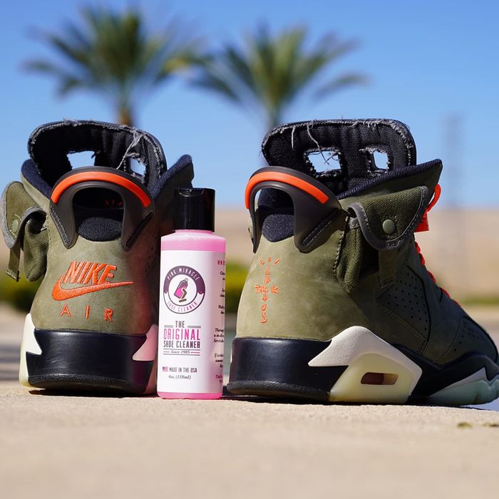 A reviewer's Nikes placed next to a bottle of the cleaning solution