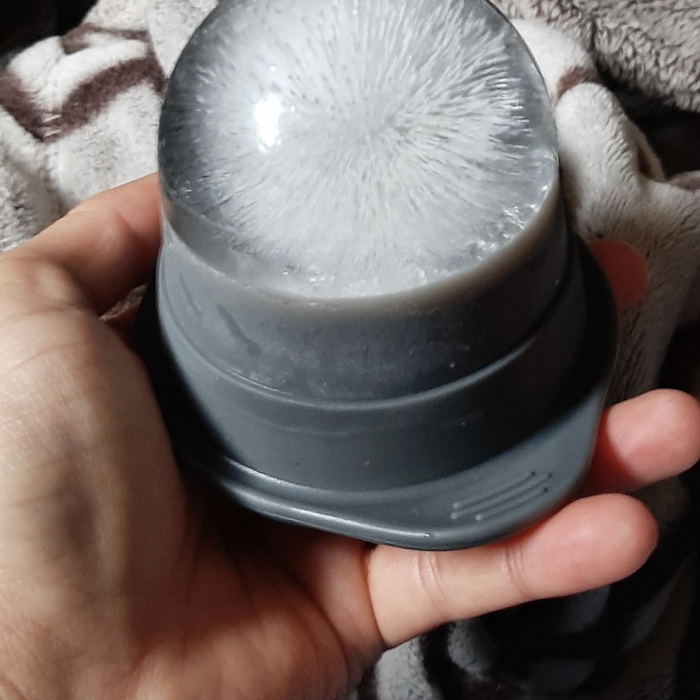 A hand grasping an ice mold, showcasing a large, fist-sized ice sphere.