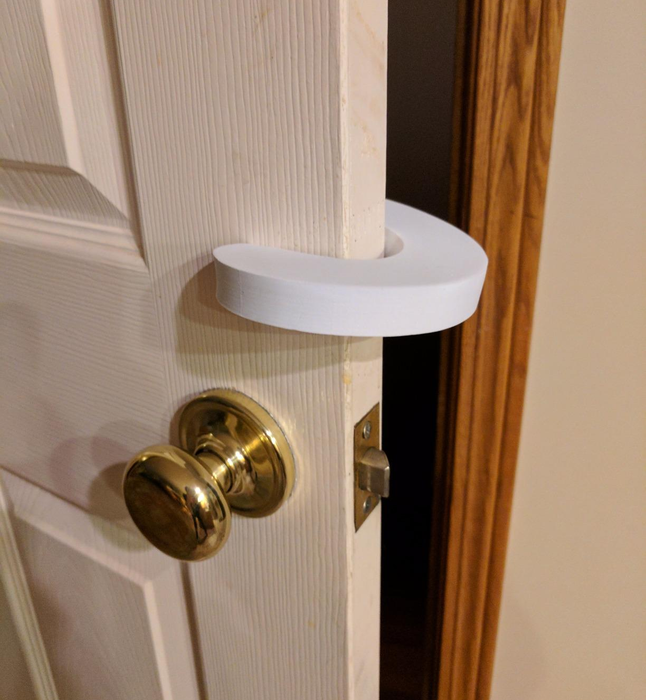 A reviewer's photo showing a pinch guard installed on a door near the knob.