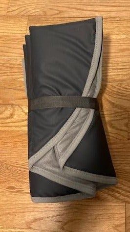 A pair of folded black workout leggings featuring a gray waistband, placed on a wooden floor.