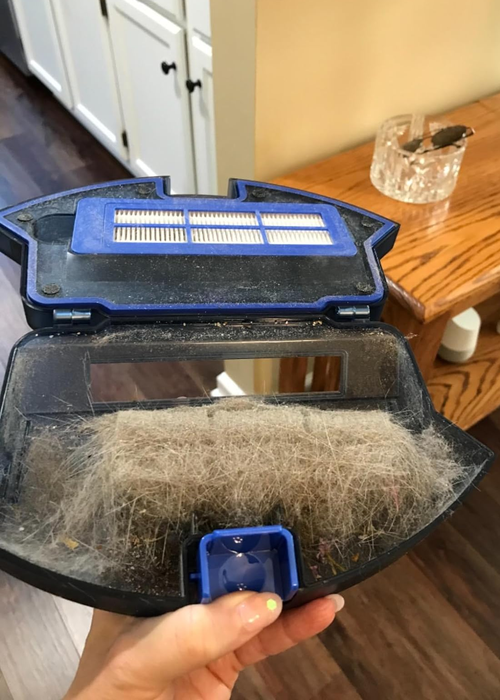 a reviewer demonstrating the impressive amount of dust and debris collected by the vacuum