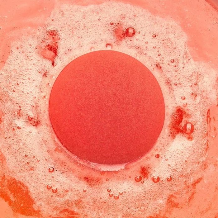 A bath bomb dissolves in the water, releasing a fizzy effect.