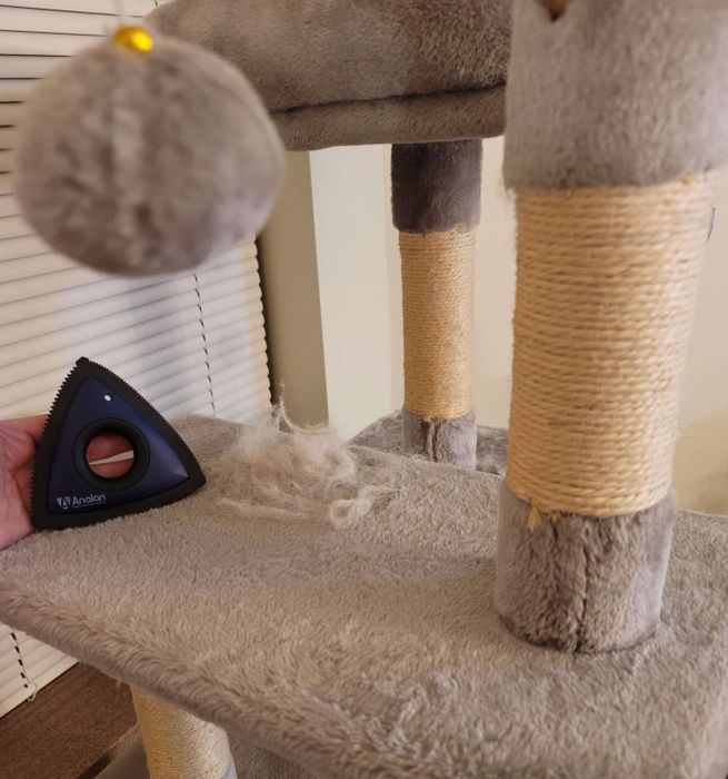 The triangular pet hair tool in action, with fur gathered from a cat tower.