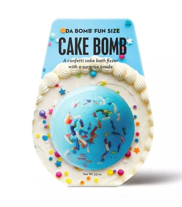 A bath bomb shaped like a cake covered in sprinkles with frosting on top.