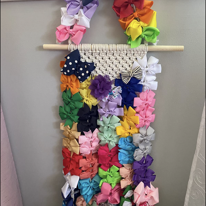 Reviewer's photo of a macrame hair accessory holder loaded with numerous hair ties and bows