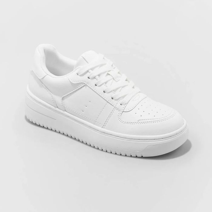 A white, low-top sneaker with a rubber sole and lace-up design, featured in a shopping-focused article.