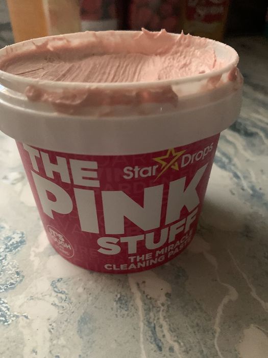A container of The Pink Stuff cleaning paste sits ready for use on a countertop.
