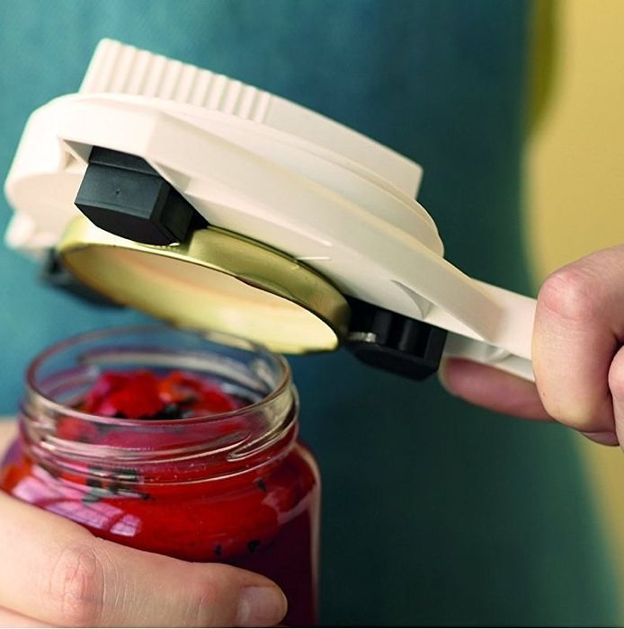 A jar opener clamped onto a jar lid, effortlessly removing it