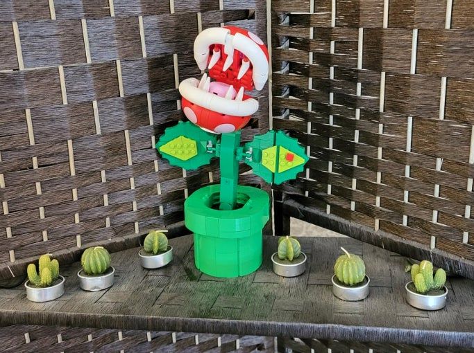 a reviewer's Lego piranha plant figure displayed alongside small cactus candles on a shelf