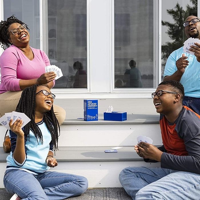 A family of four enjoying a lively game of 'Kids Against Maturity' together.