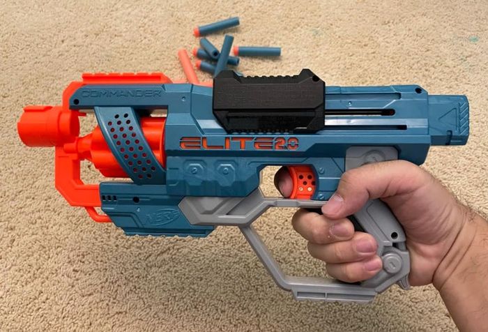 a reviewer holding their Nerf blaster with foam darts displayed behind it